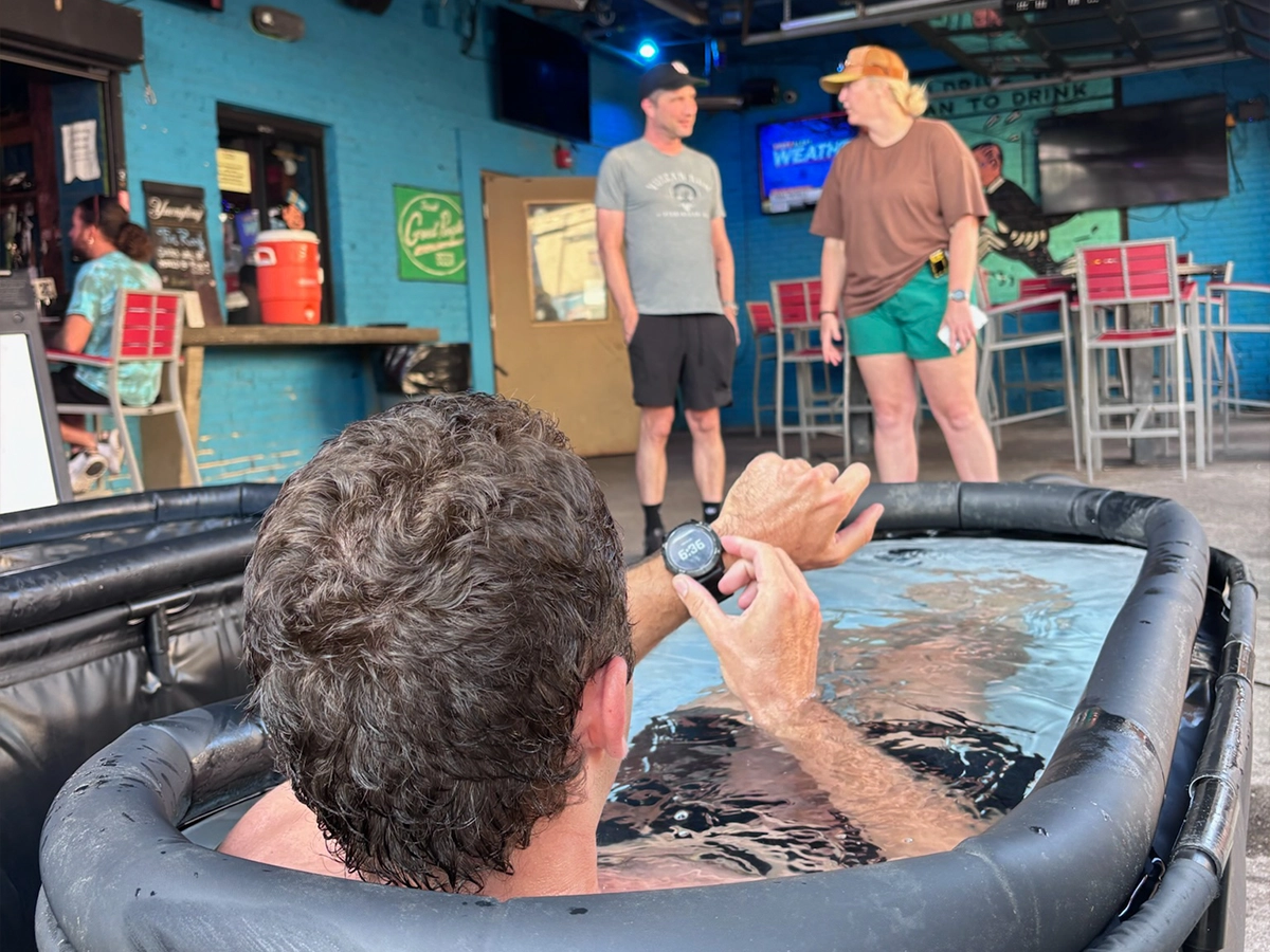 Man checking his watch while cold plunging at an R3 Contrast pop-up event