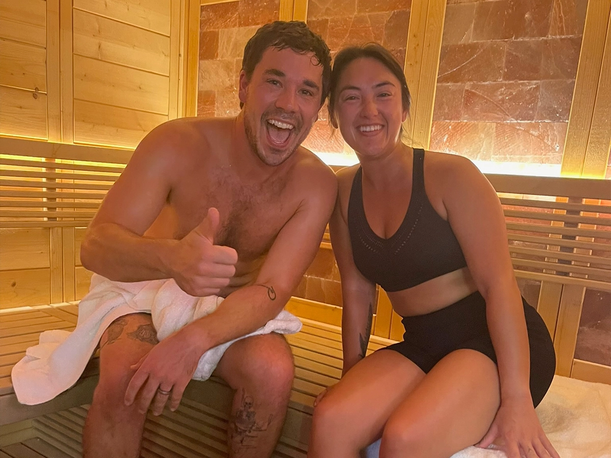 Smiling couple sitting together on the salt-panel sauna bench at R3 Contrast